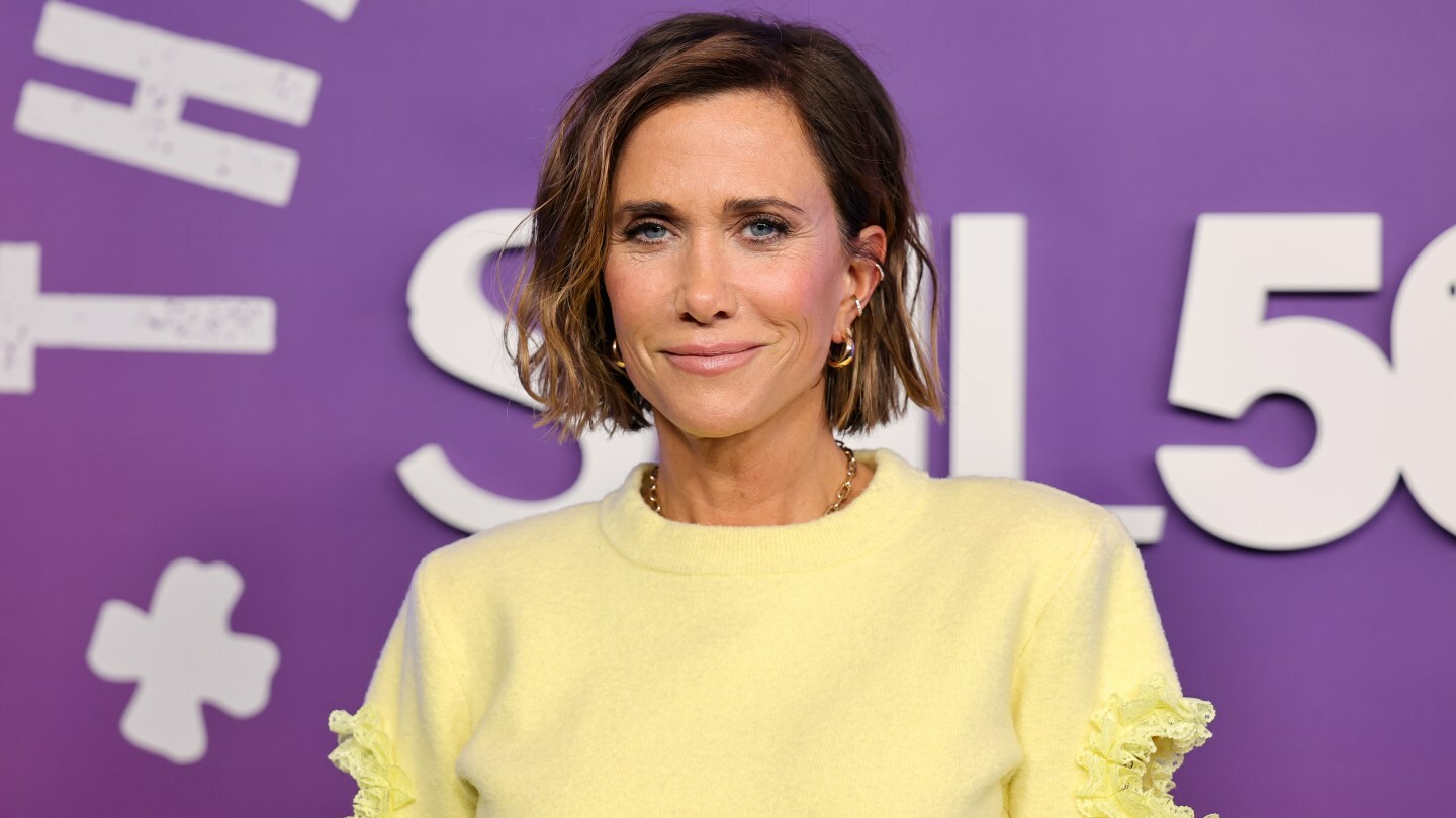 Kristen Wiig poses in a yellow sweater.