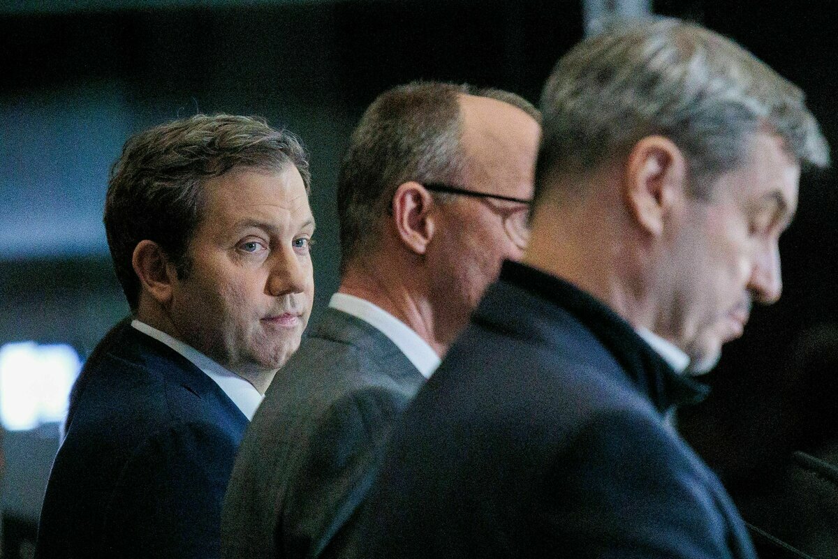Klingbeil schaut auf Merz und Söder bei einer Pressekonferenz.