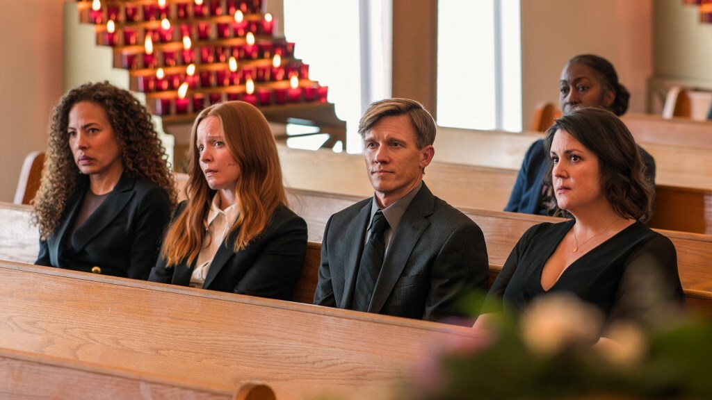 Tawny Cypress, Lauren Ambrose, Warren Kole and Melanie Lynskey wear black and sit on a church pew in a still from 'Yellowjackets'.