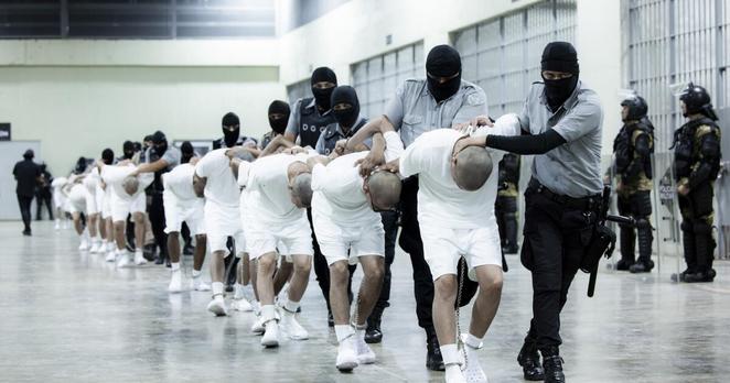 In this photo provided by El Salvador's presidential press office, prison guards transfer deportees from the U.S., alleged to be Venezuelan gang members, to the Terrorism Confinement Center in Tecoluca, El Salvador, Sunday, March 16, 2025. (El Salvador presidential press office via AP)