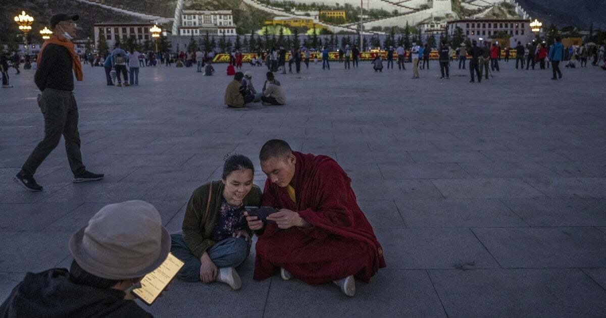 A Tibetan Buddhist monk and a woman share a mobile phone outside the Potala Palace in Lhasa, Tibet Autonomous Region, China, on June 1, 2021.