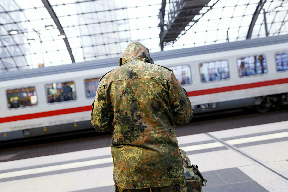 Ein Bundeswehrsoldat reist mit der Bahn und wartet im Bahnhof auf seinen Zug