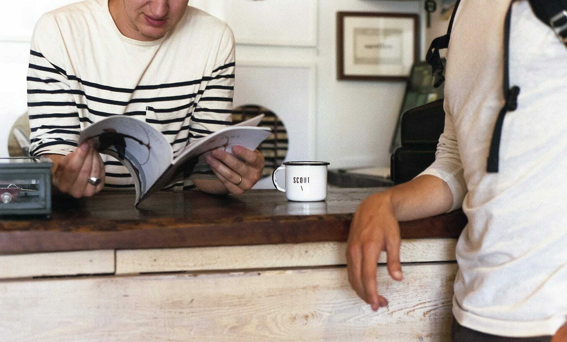 Book Publishing Terms -A person reading a book on a desk with a friend nearby