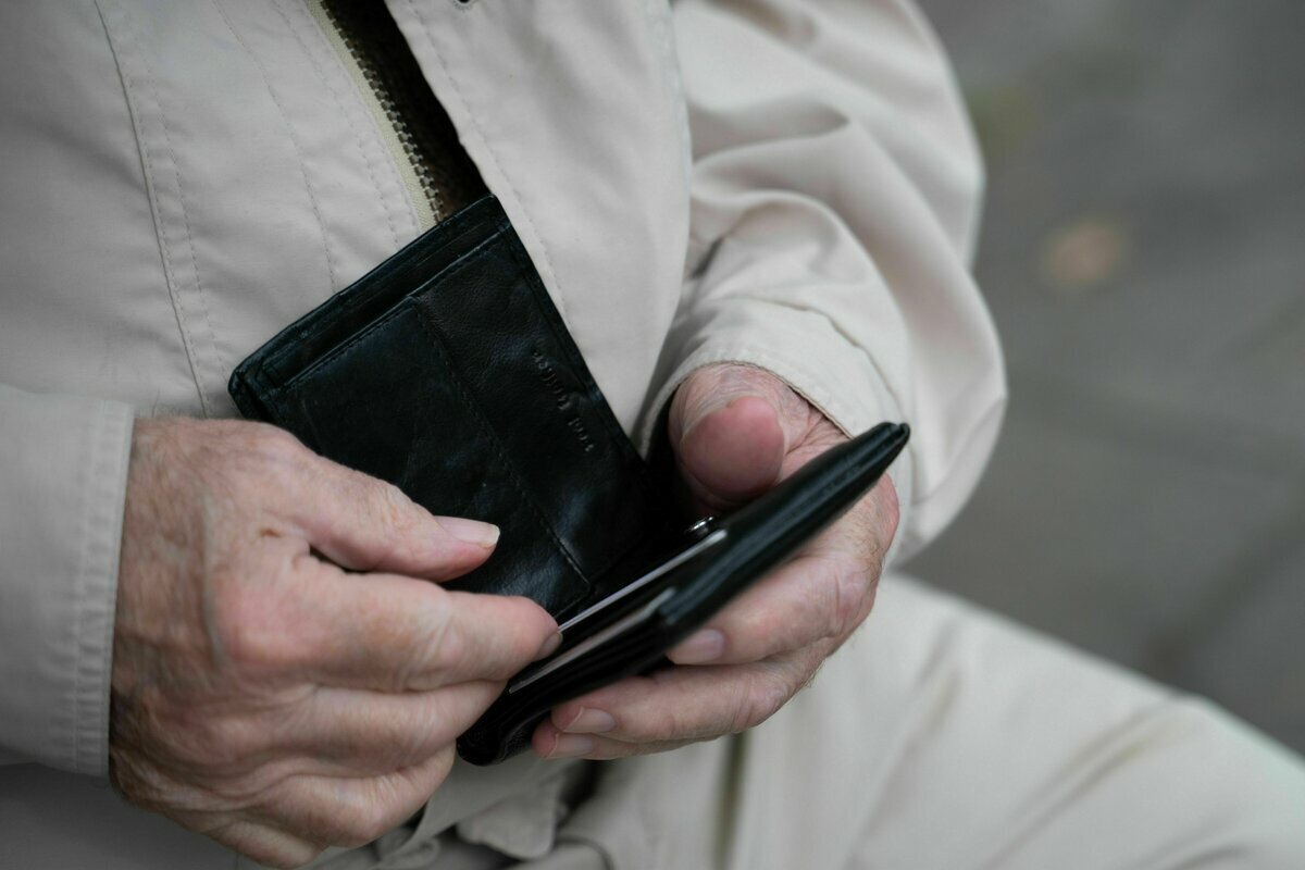 Ein Rentner hält sein leeres Portemonnaie in der Hand