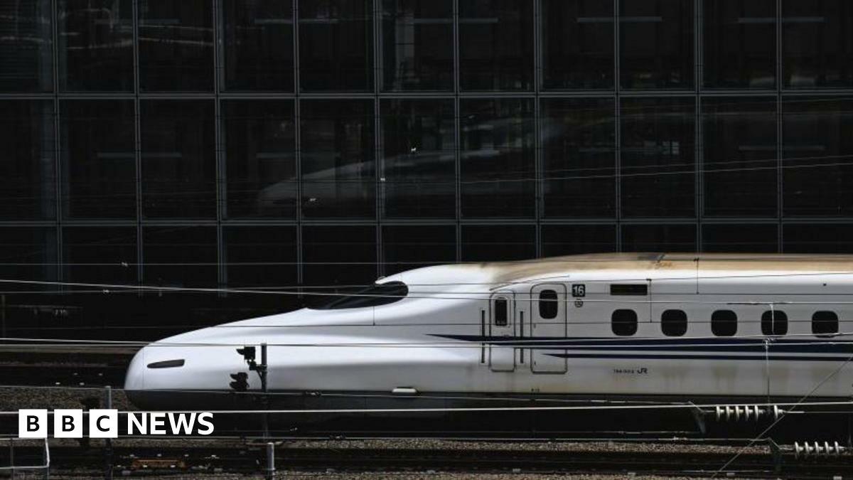 Bullet train facing left as it pulls into Tokyo station. 