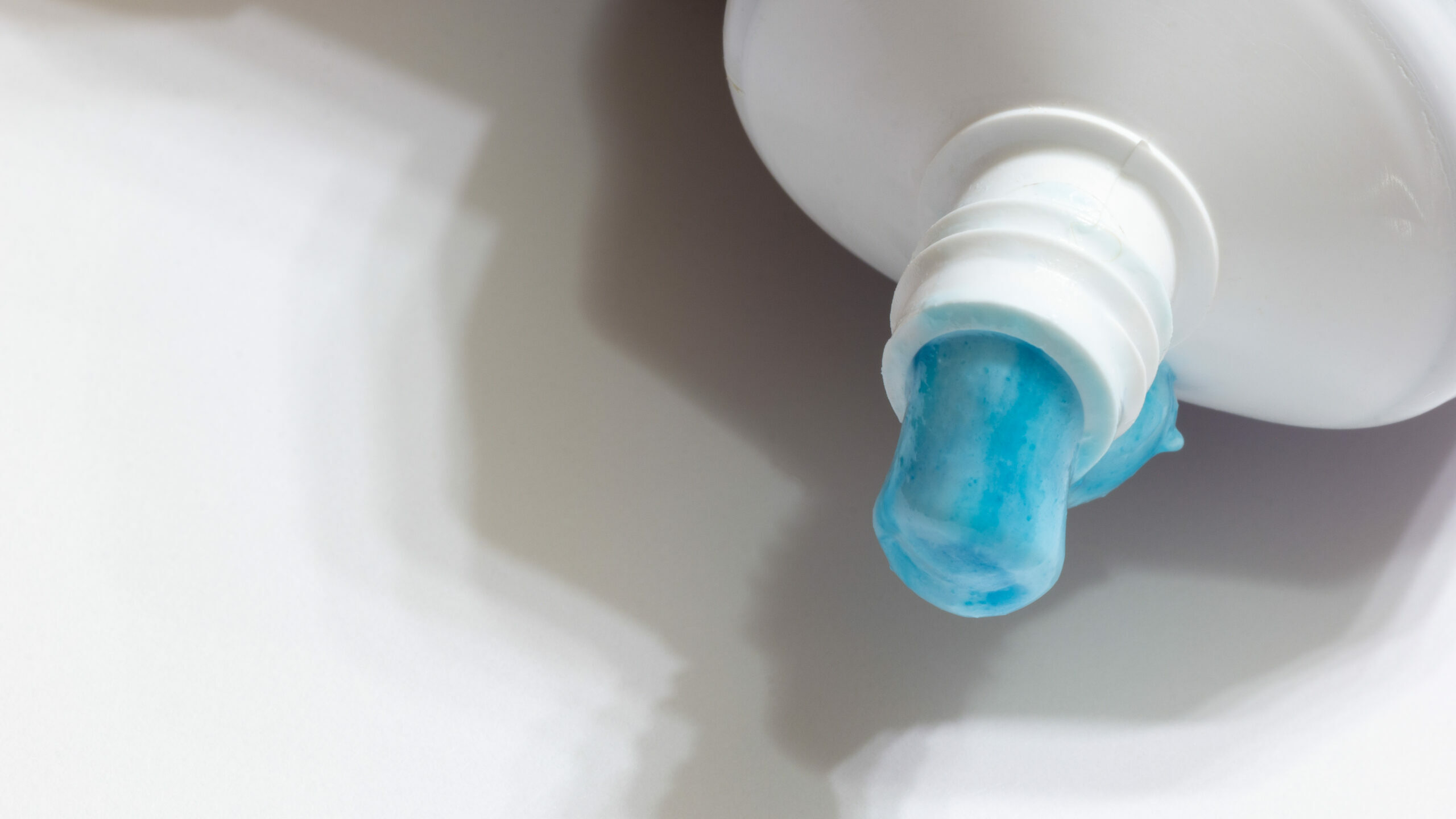 blue toothpaste oozing from a white tube blue toothpaste oozing from a white tube