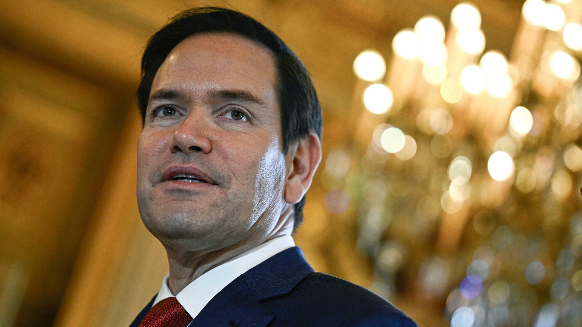US-Außenminister Marco Rubio vor einem Kronleuchter im Hintergrund.