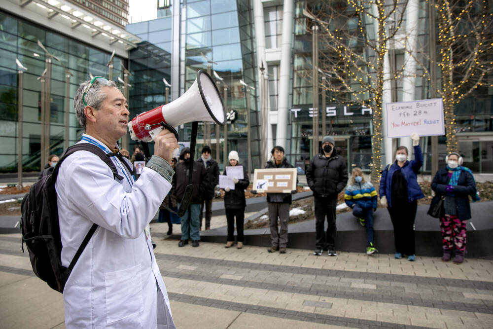BU professor Nathan Phillips leads a chant as protesters call for a boycott of Tesla, outside the company's showroom on Boylston St. in Boston. (Robin Lubbock/WBUR)