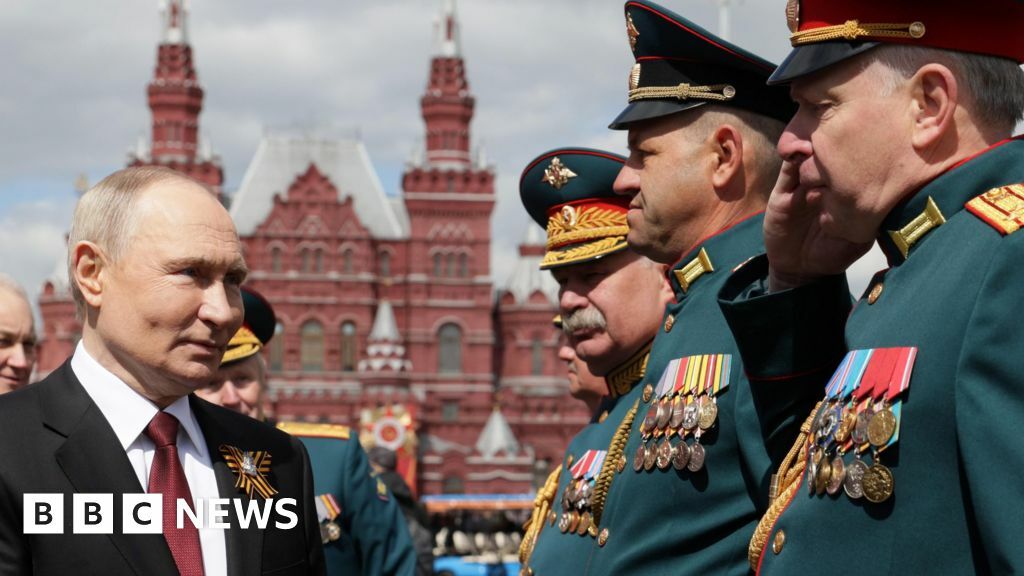 Putin shakes hands with men wearing military dress uniform in Red Square