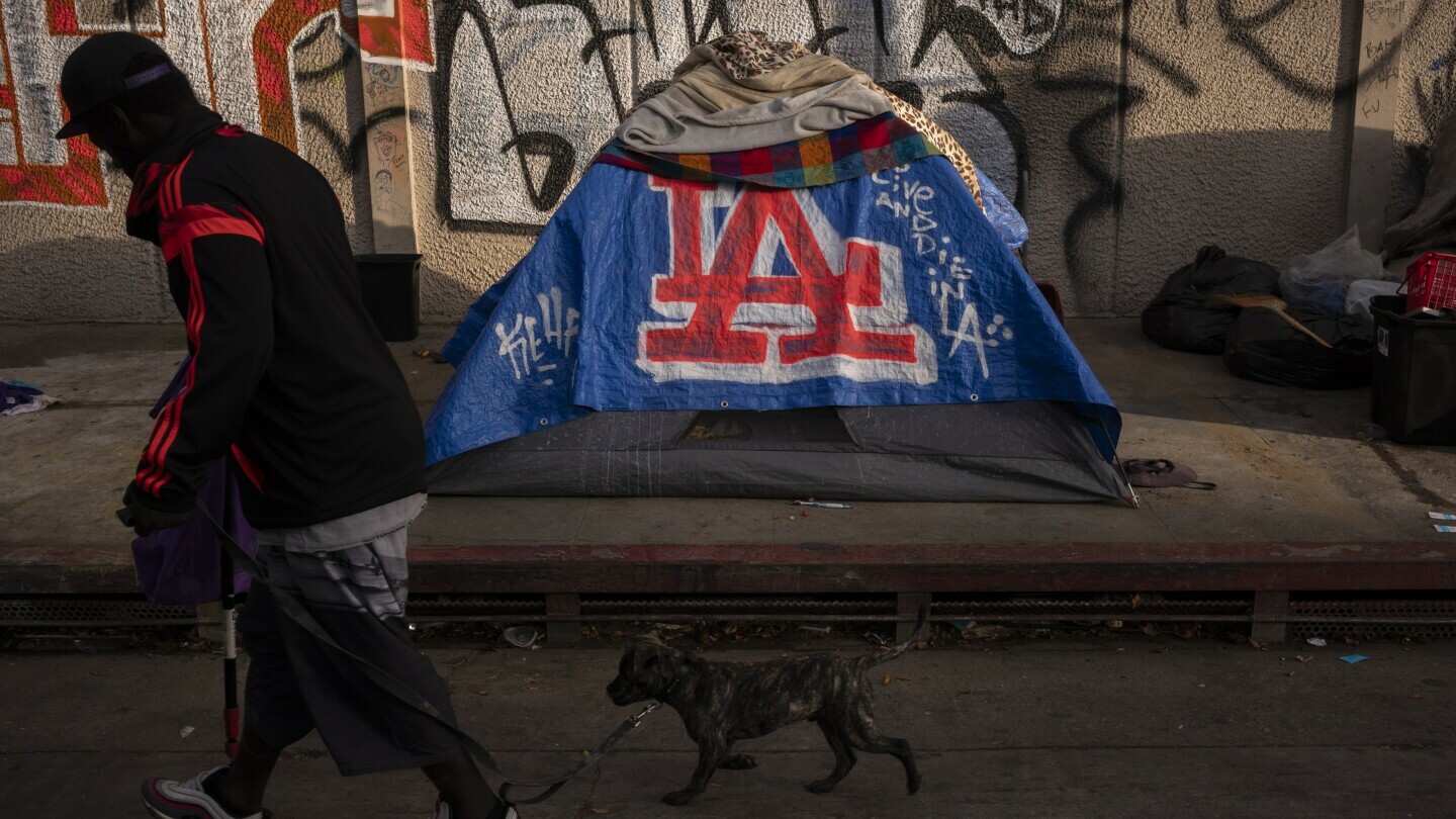 A man walks past a homeless encampment in downtown Los Angeles, Oct. 25, 2023. (AP Photo/Jae C. Hong, File)