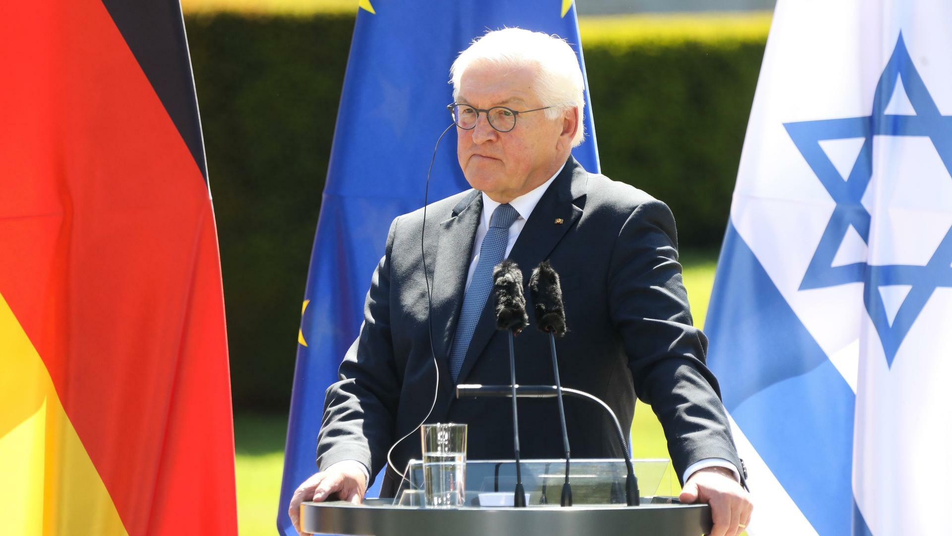 Bundespräsident Frank Walter Steinmeier bei der Pressekonferenz im Schloss Bellevue in Berlin. Er steht an einem Redepult. Hinter ihm sind die deutsche, die israelische und die EU-Flagge zu sehen. 