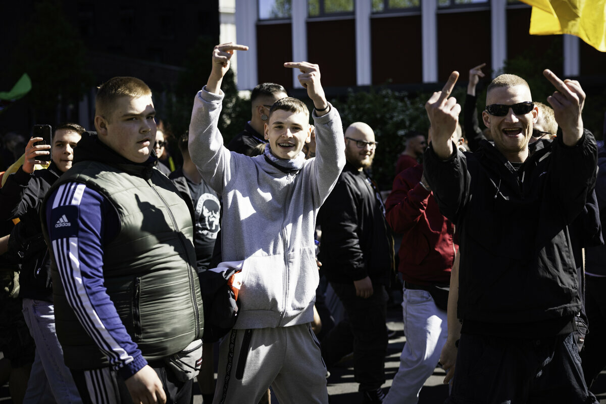 Rechte Demonstranten feixen und zeigen den Stinkefinger