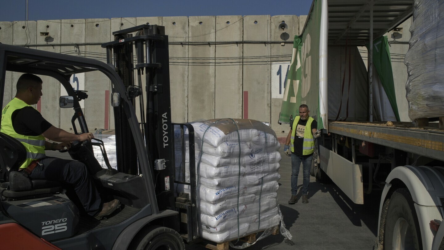 Workers unload cargo from a truck carrying humanitarian aid for the Gaza Strip at the offload area of the Kerem Shalom border crossing between Israel and Gaza, southern Israel, Thursday, May 22, 2025. (AP Photo/Leo Correa)
