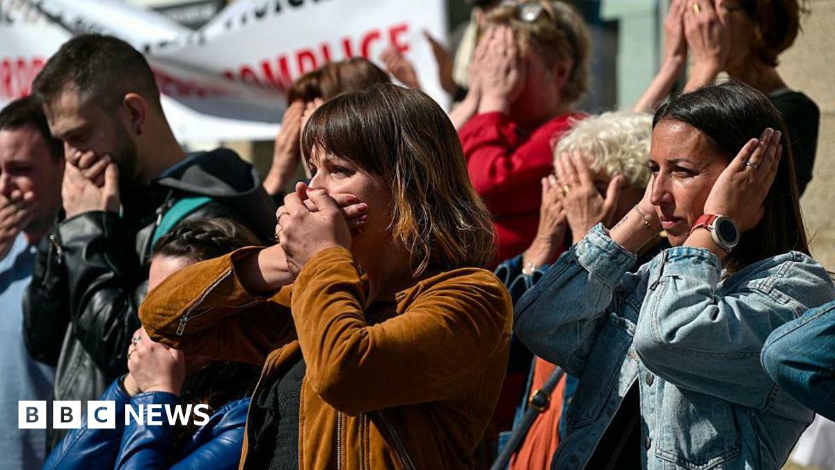 Men and women outside a courthouse in France hold their hands over their mouths in protest. | Getty Images