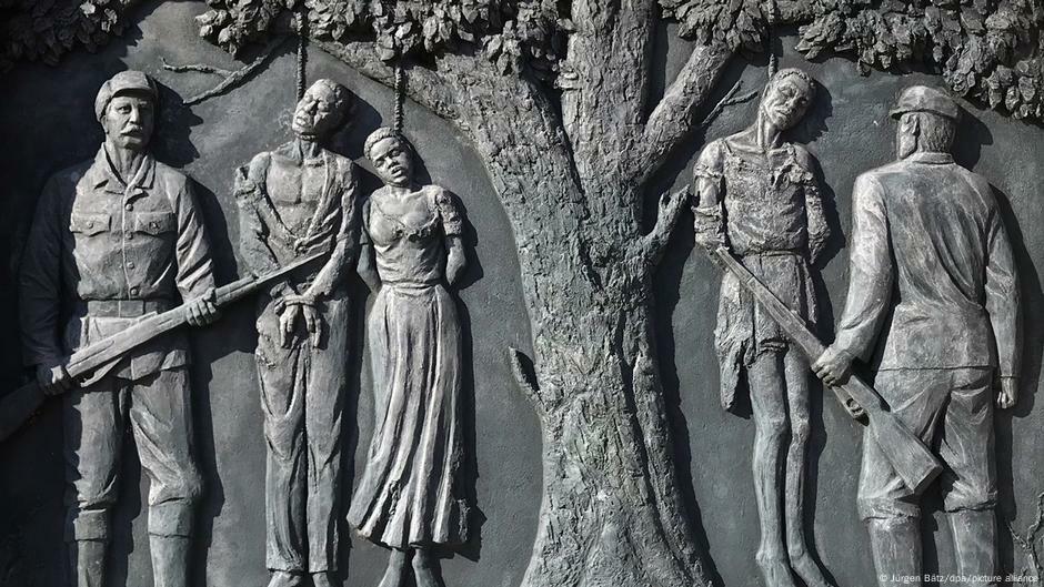 Monumento mostra herero enforcados nos galhos de uma árvore e soldados alemães com fuzis Monumento mostra herero enforcados nos galhos de uma árvore e soldados alemães com fuzis