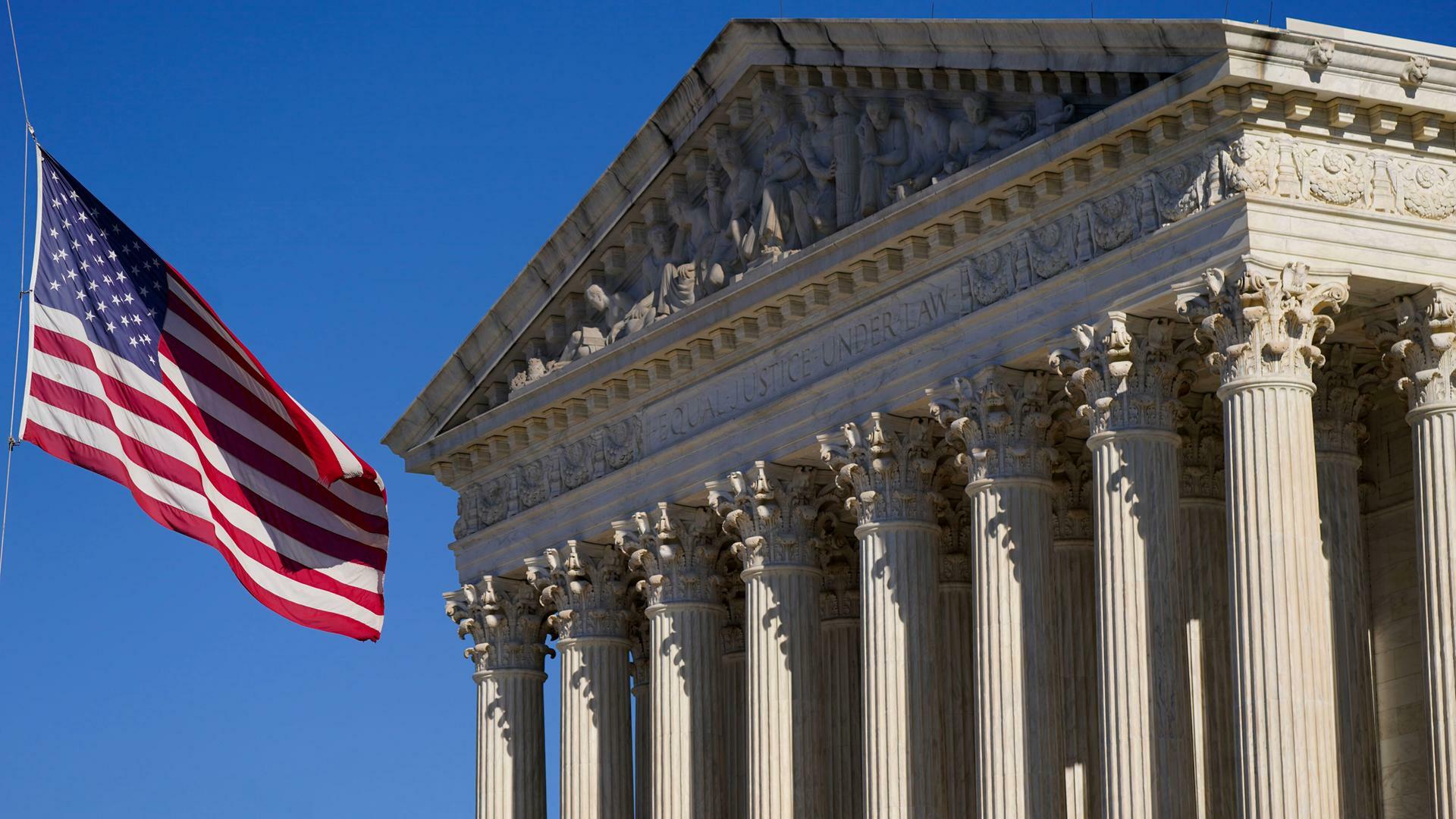 Eine US-Flagge weht im Wind vor dem Gebäude des Supreme Court in Washington mit der Inschrift "Equal justice under law".