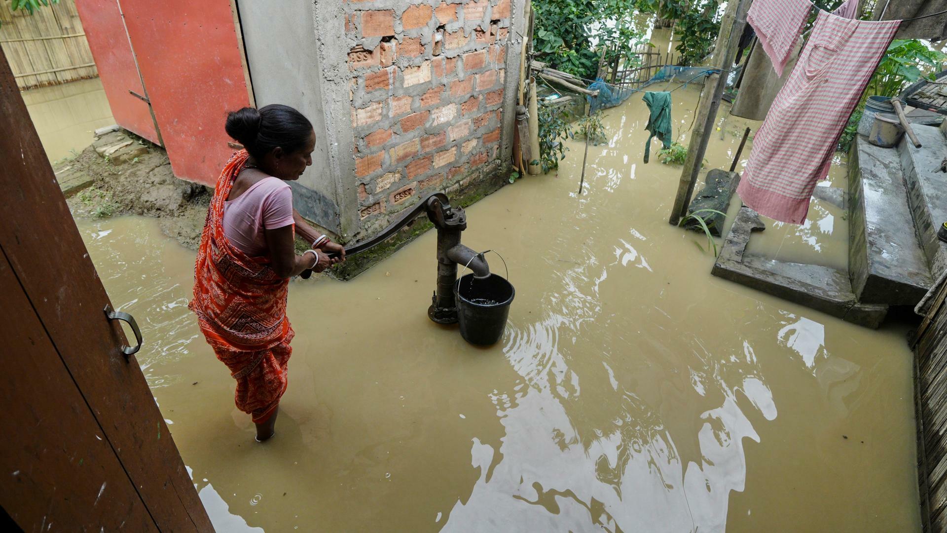 Indien, Kampur: Eine Frau benutzt eine Handpumpe, um Wasser inmitten der überfluteten Umgebung ihres Hauses nach tagelangen sintflutartigen Monsunregenfällen zu sammeln. Indien, Kampur: Eine Frau benutzt eine Handpumpe, um Wasser inmitten der überfluteten Umgebung ihres Hauses nach tagelangen sintflutartigen Monsunregenfällen zu sammeln.