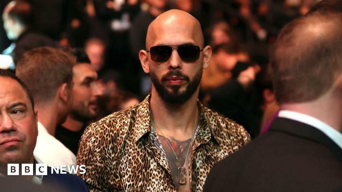 Andrew Tate wearing dark sunglasses and a button-down animal print shirt and a dogtag necklace