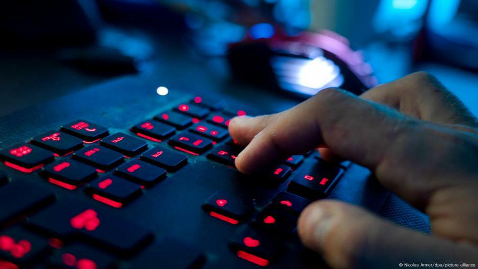 Männerhände auf einer beleuchteten Computertastatur