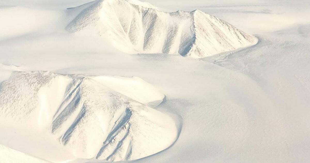 Landschaft mit zwei Bergen, die komplett mit Schnee bedeckt ist