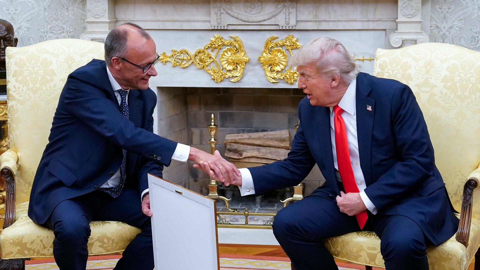 Bundeskanzler Friedrich Merz schüttelt im Oval Office die Hand von US-Präsident Donald Trump. In der anderen Hand hält Merz sein Gastgeschenk: ein gerahmtes Abbild der Geburtsurkunde von Trumps Großvater.