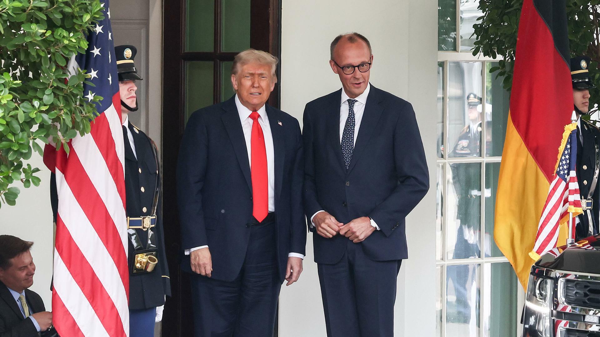 US-Präsident Donald Trump und Bundeskanzler Friedrich Merz nebeneinander vor dem Weißen Haus, neben ihnen sind die amerikanische und die deutsche Flagge gehisst.