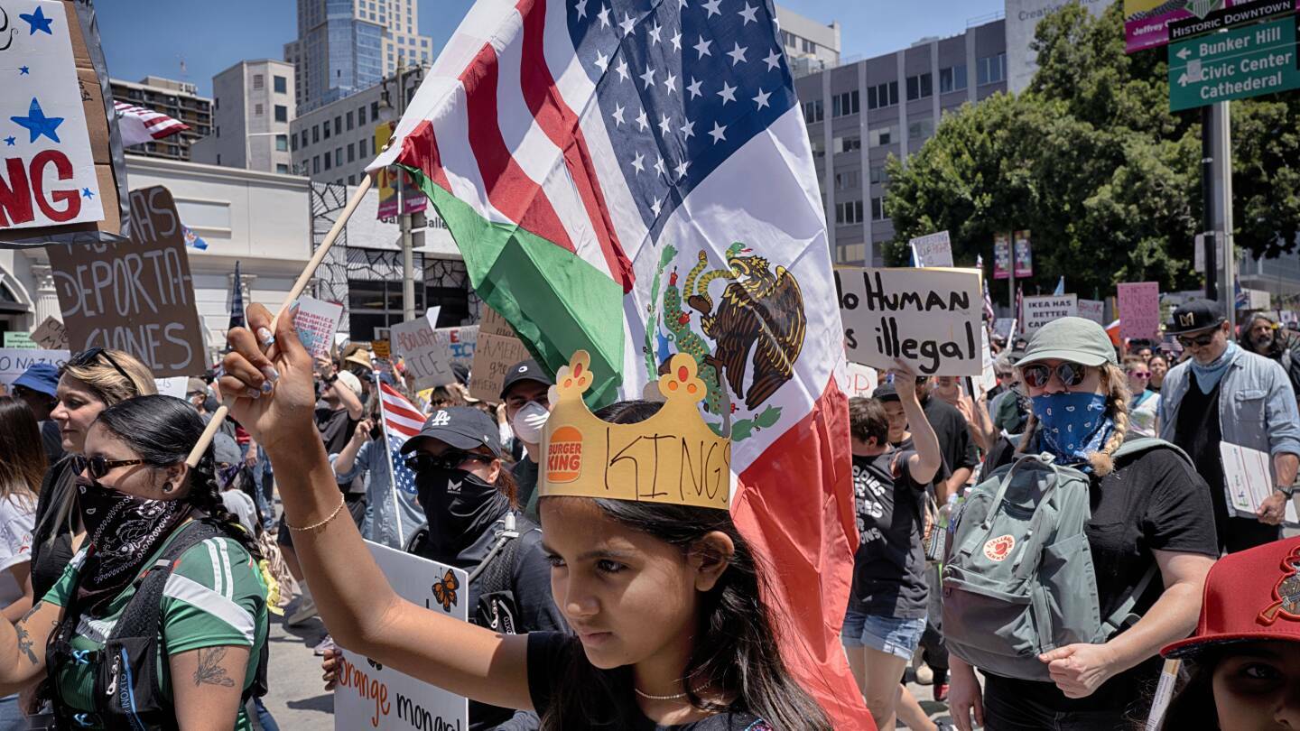 A young protester carries a combination Mexican and U.S. flag during a "No Kings" protest in downtown Los Angeles on Saturday, June 14, 2025. (AP Photo/Richard Vogel)