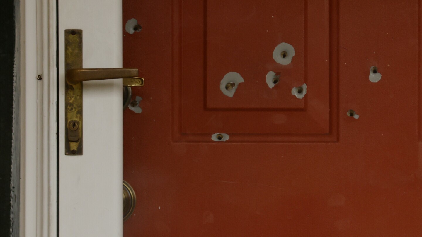 Bullet holes mark the front door of the house of Minnesota state Sen. John Hoffman and his wife who were shot earlier in the day, Saturday, June 14, 2025, in Champlin, Minn. (AP Photo/Bruce Kluckhohn)