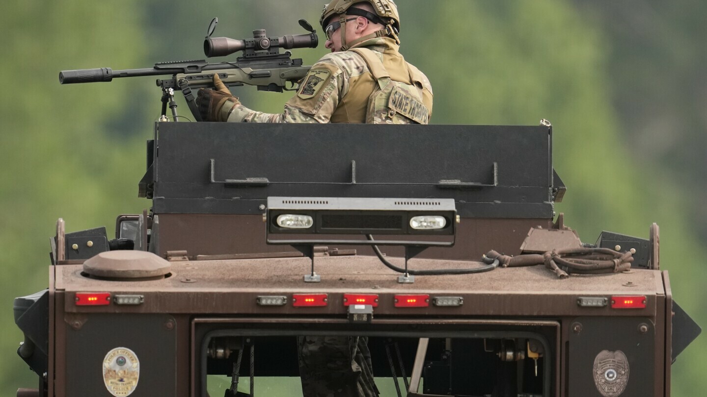 A law enforcement officer trains his rifle towards a house as the officers search for shooting suspect, Vance Boelter, Sunday, June 15, 2025, in Belle Plaine, Minn. (AP Photo/George Walker IV)