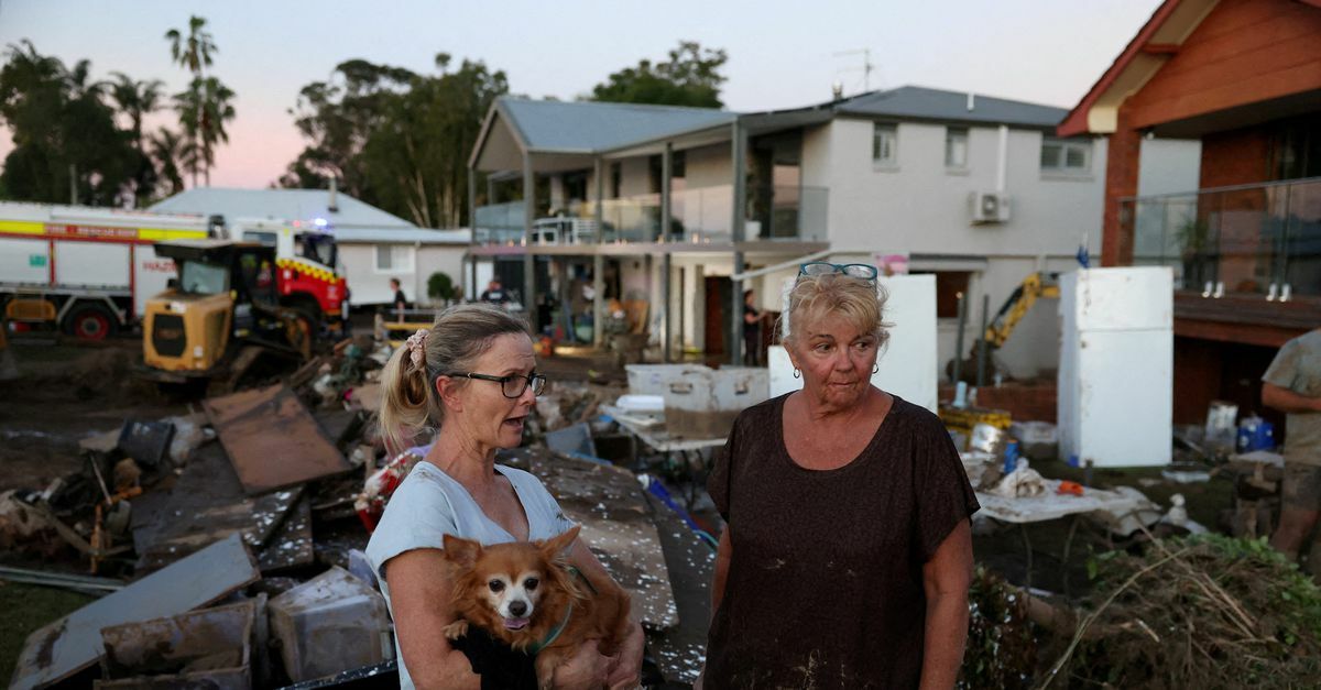 Twee vrouwen staan voor een verwoest huis door een overstroming in Australië, mei 2024. Foto: Hollie Adams/ Reuters
