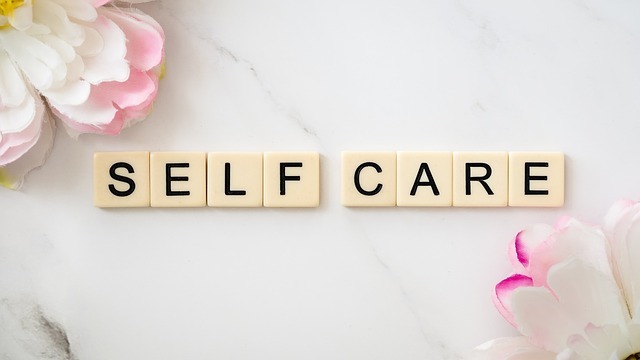 tile blocks reading "self care" on white background with pink and white flowers in the corners, a serene scene