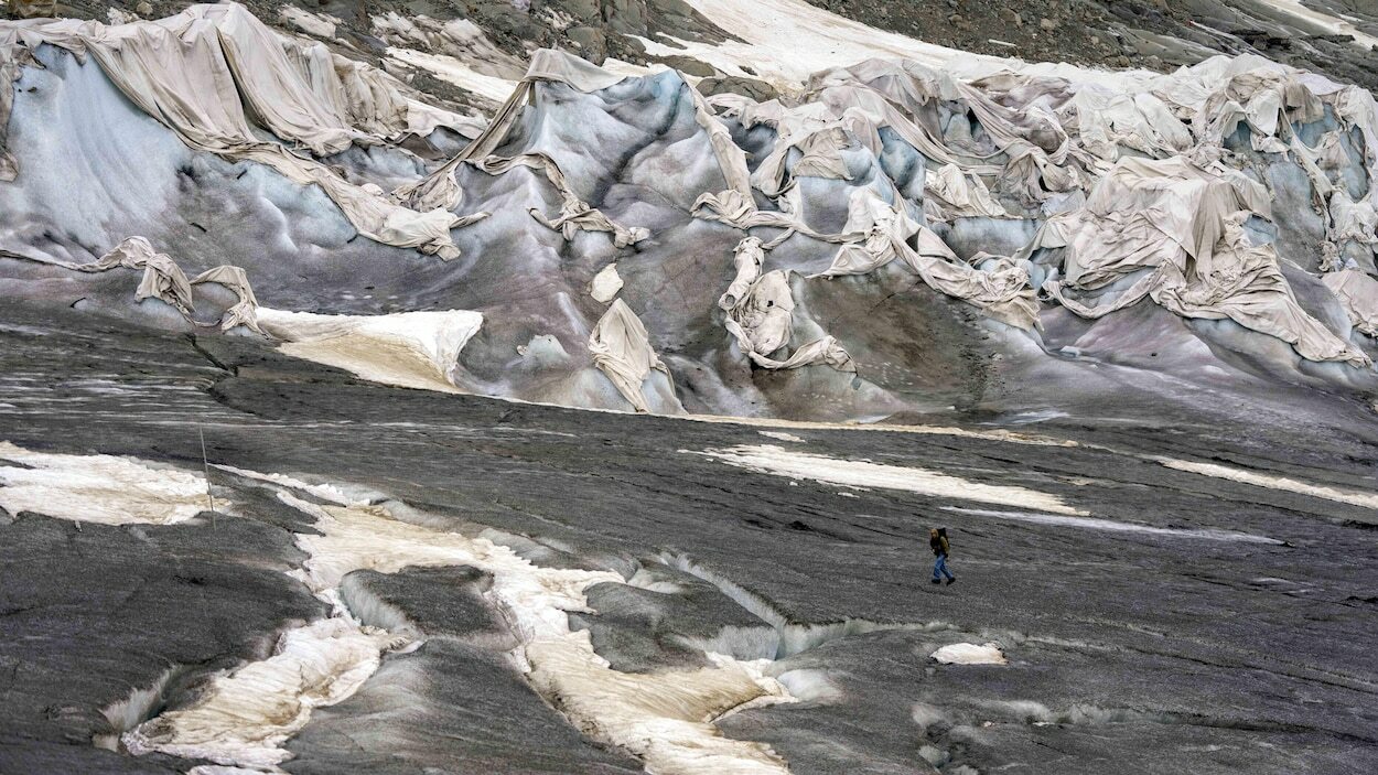 Un glacier fond en montagne malgré d'immenses toiles étendues sur la glace.