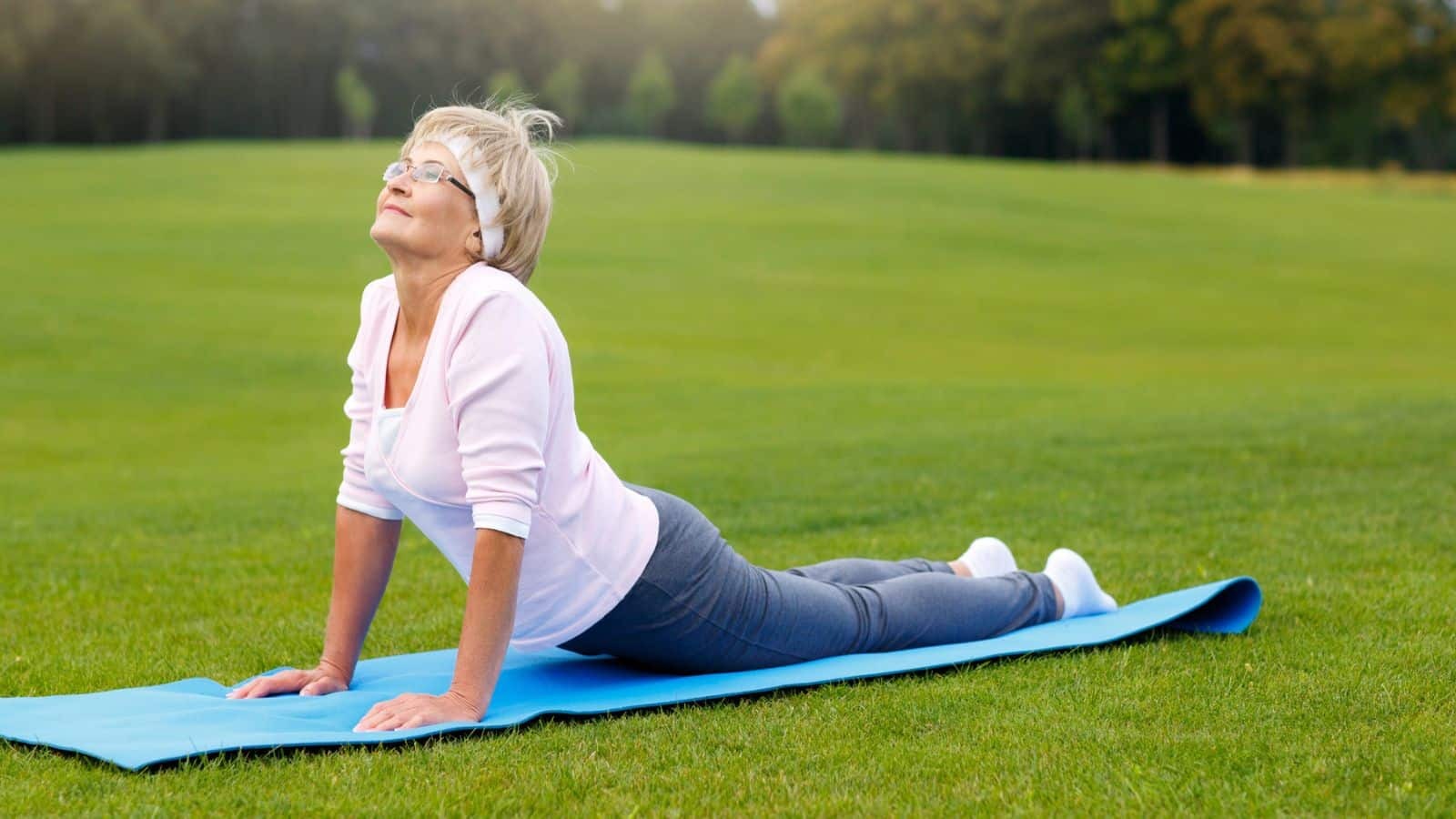 Mature woman stretching in a field on a yoga mat