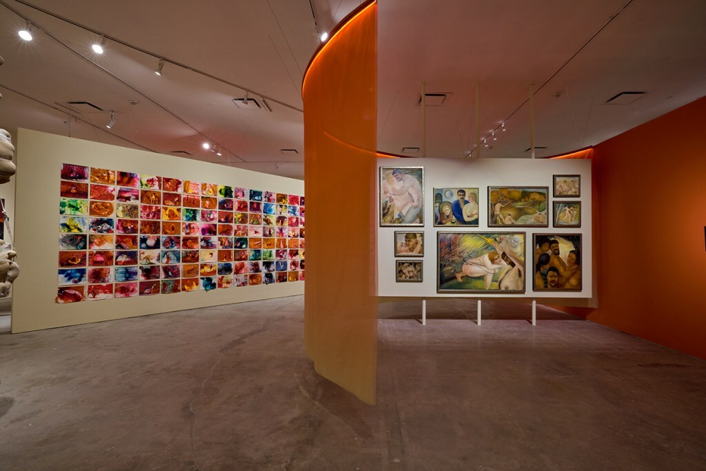 A bright orange curtain divides a room. On a left, a grid of xozens of abstract paintings. On the right, 9 erotic paintings. Details not visible from this distance.