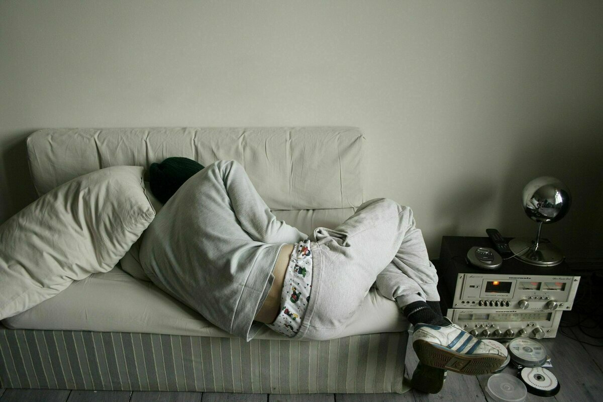 Ein junger Mann schläft auf einem Sofa, das viel zu klein für ihn ist