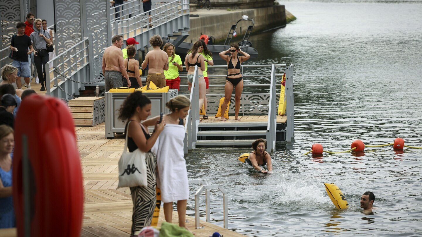 A woman dives in the water as people swim at the Pont Marie safe bathing site on the Seine river in Paris, France, Saturday, July 5, 2025, during the opening of the three Seine swimming pools, as part of the 'Paris Plages' event. (AP Photo/Thomas Padilla)