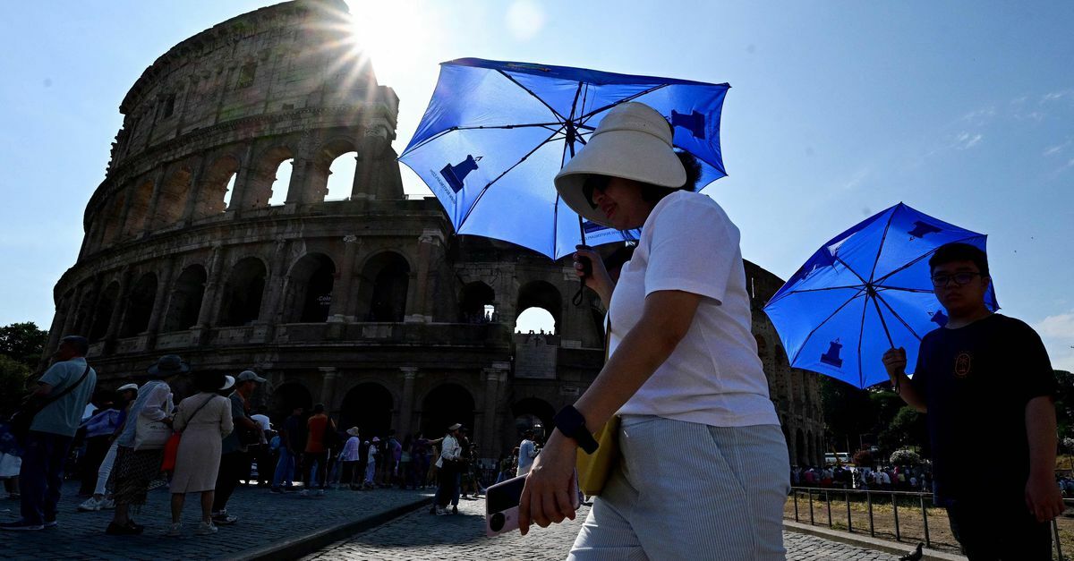 Vrouw beschermt zichzelf tegen de zon met een paraplu, bij het Colosseum in Rome. 