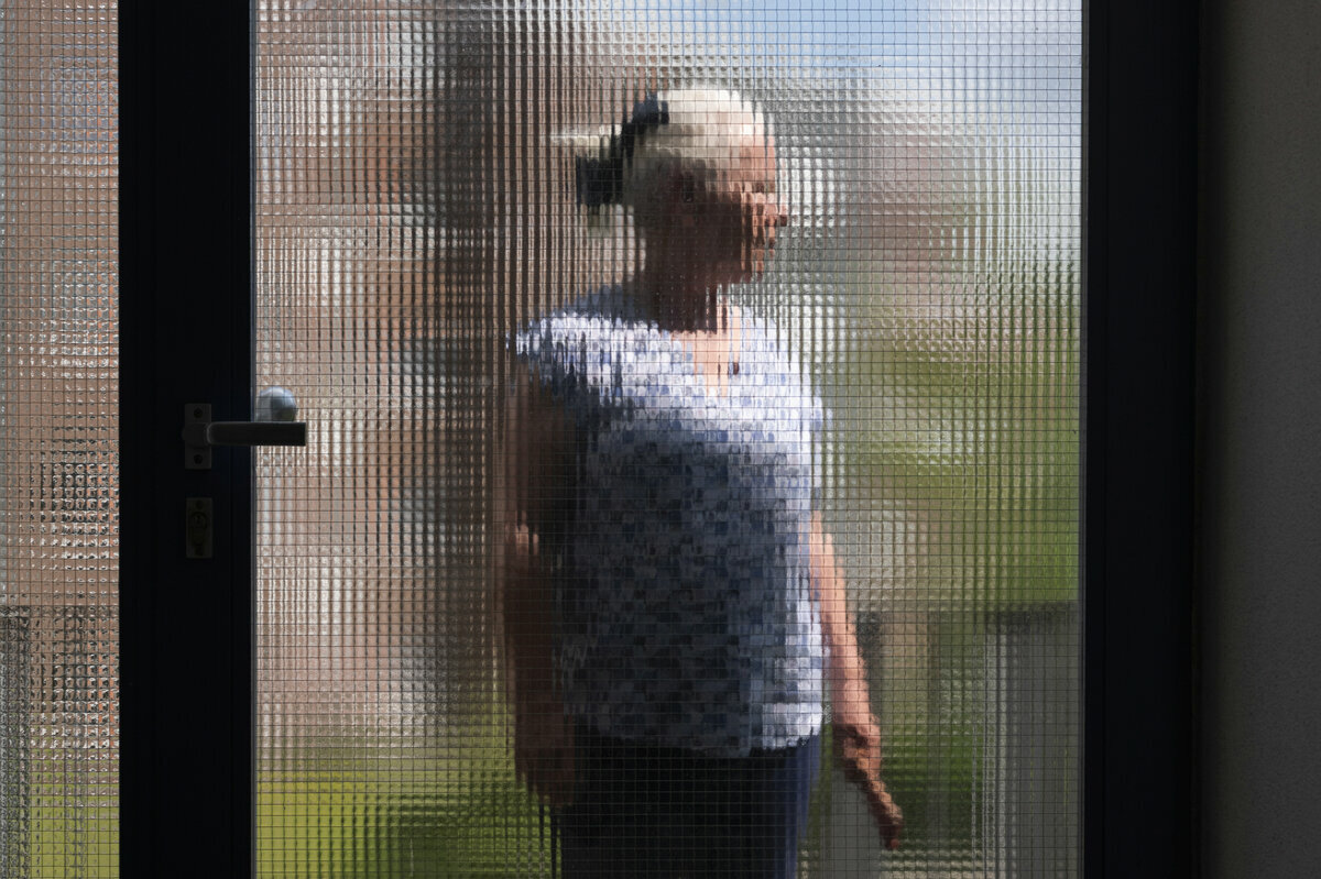 Eine Person ist anonymisiert hinter einer Scheibe fotografiert.