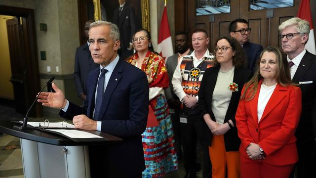 Le premier ministre Mark Carney est accompagné de membres de son cabinet et de son caucus lors d'une conférence de presse dans le foyer de la Chambre des communes à Ottawa.