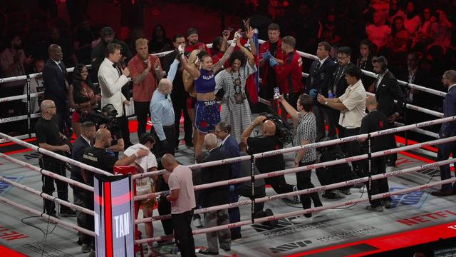 Des dizaines de personnes se trouvent sur un ring de boxe.