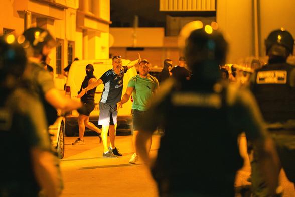 Randalierer vor einer Polizeikette.