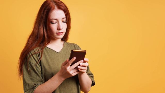 Junge Frau, die etwas auf ihrem Smartphone liest