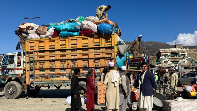 Afghanen vor einem Lkw, der mit Säcken und Gepäck beladen ist