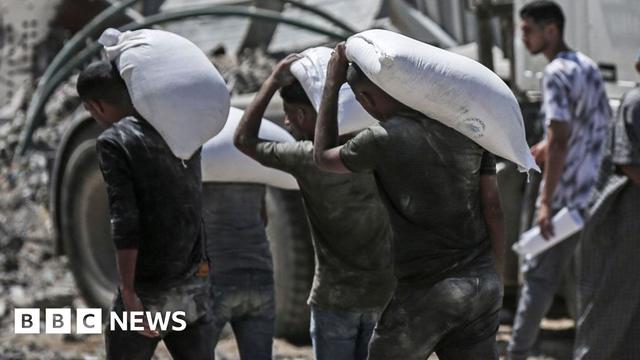 Palestinians carry food collected from a humanitarian aid distribution point in Beit Lahia, northern Gaza, on Sunday, July 20, 2025.