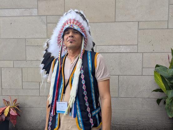Man in traditional garb poses in front of a wall.