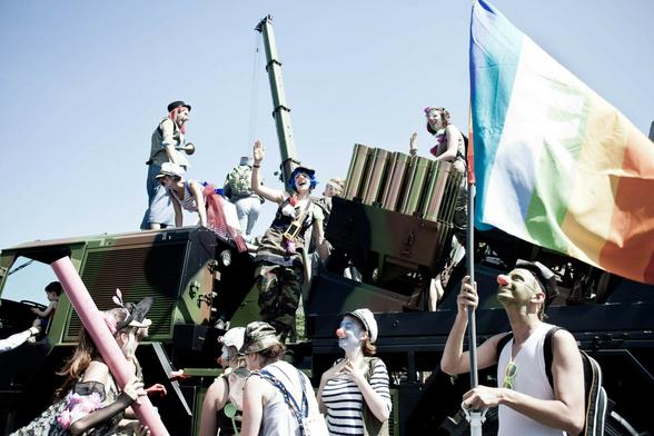 Menschen mit schminke auf dem Gesicht und roten Nasen lachen und halten eine Regenbogenflagge Menschen mit schminke auf dem Gesicht und roten Nasen lachen und halten eine Regenbogenflagge