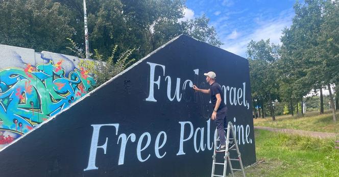 Graffitispuiter Niels Bakkerus vult, op woensdag, de krijtlijnen van de ‘c’ op met zijn spuitbus. Foto Pim van der Hulst