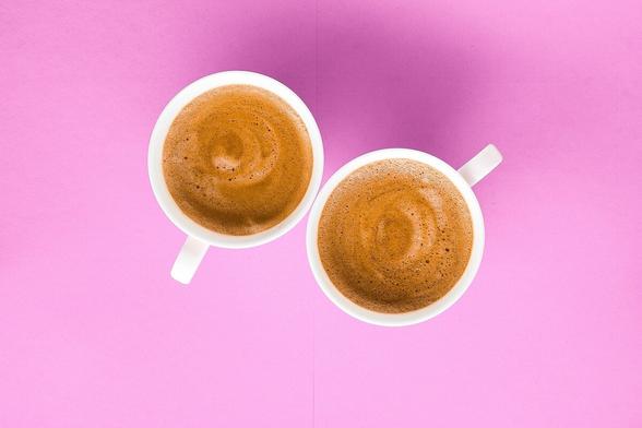 Zwei Espressotassen vor pinkfarbenem Hintergrund