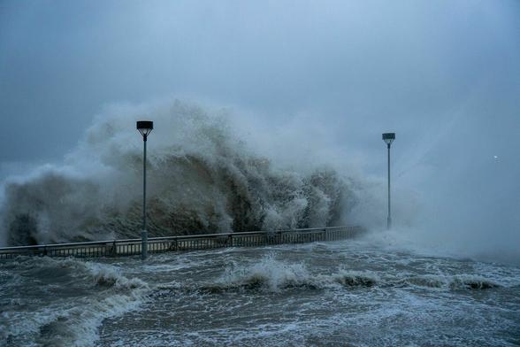 Eine große Welle überschwemmt eine Uferpromenade