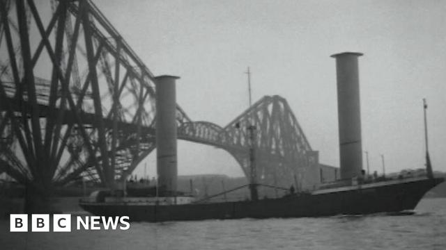Black and white image of the Buckau, with a black hull and two large towers sticking up from the deck. It has just passed under the iconic Forth Bridge Black and white image of the Buckau, with a black hull and two large towers sticking up from the deck. It has just passed under the iconic Forth Bridge
